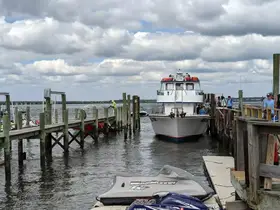 A boat approaches the dock with several people visible, creating a lively atmosphere at the marina. Jet skis are also present, highlighting the excitement of water activities.