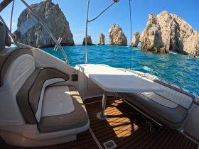 A cozy seating area inside a boat, featuring a table and comfortable cushions, with stunning rock formations visible in the background — perfect for enjoying the scenic views while cruising.