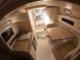 Interior view of a cozy boat cabin featuring a dining area and kitchenette, perfect for relaxing and entertaining while on the water.