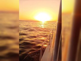 A stunning sunset view from the side of a boat, showcasing the tranquil waters and vibrant colors of the evening sky — perfect for romantic evening cruises.