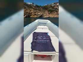 A cozy seating area on a boat featuring a branded towel from Archipelago Cruises, perfect for relaxing on the water with stunning coastal views.