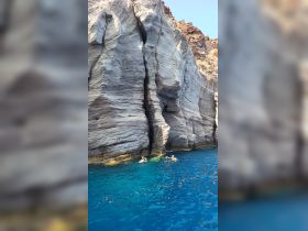 Two swimmers enjoy the vibrant blue waters near stunning rock formations, capturing the essence of a perfect day on the water.