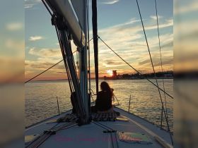 A serene sunset view from a sailing boat in Lisbon, with a guest enjoying the picturesque scenery — perfect for romantic evenings on the water.