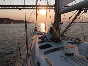 A couple enjoys a serene sunset while sailing on a yacht, creating a romantic atmosphere perfect for evening cruises.