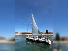 A lively group enjoys a sailing experience on a beautiful day, with the stunning backdrop of architecture and clear blue skies.