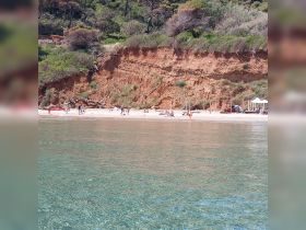 A vibrant beach scene with groups of people enjoying the sun and water, set against a stunning coastal backdrop — perfect for summer outings and family fun.