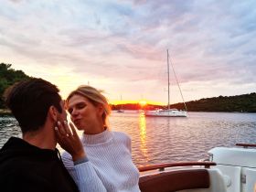 A couple shares a romantic moment on a yacht at sunset, creating the perfect backdrop for love and celebration on the water.