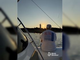 A serene sunset view from a boat, featuring a person admiring the lighthouse in the distance — a perfect moment for relaxation and reflection on the water.