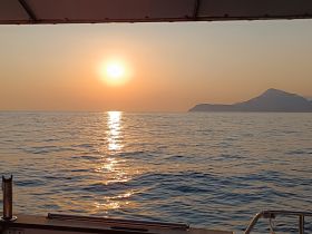 A serene sunset view over calm waters, captured from the deck of a boat, showcasing the beauty of nature and the tranquility of a boating experience.