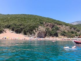 A vibrant beach scene with people enjoying the sun and swimming in crystal-clear waters, perfect for a summer getaway.