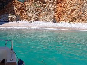 A stunning view of a secluded beach with crystal-clear waters and rocky cliffs, perfect for a relaxing day on the water.