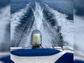 A dynamic view from the back of a speedboat, showcasing the powerful engine and the wake created as it glides through the clear blue waters.