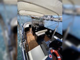 An inviting view of the helm and seating area inside a boat, showcasing the elegant wooden flooring and well-equipped console, perfect for a comfortable day on the water.