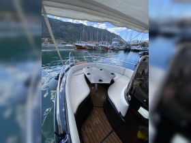 A cozy interior view of a boat's seating area, featuring comfortable cushions and a stylish table, perfect for relaxing while enjoying the surrounding marina scenery.
