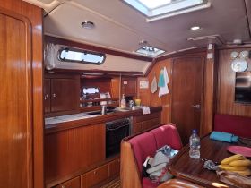 Interior view of a well-equipped boat cabin featuring a cozy seating area and kitchen space, perfect for relaxing during your nautical adventures.