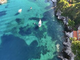 Aerial view of a yacht navigating through crystal-clear waters, showcasing the stunning coastal scenery and vibrant marine life.
