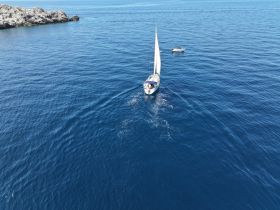 Aerial view of a sailboat gracefully navigating through deep blue waters, showcasing the beauty of sailing adventures.