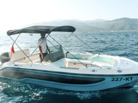 A man navigates a sleek boat on the open water, showcasing the perfect blend of adventure and relaxation on a sunny day.