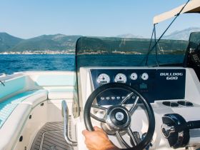 A close-up view of the helm of a Bulldog 600 boat, showcasing the steering wheel and dashboard, perfect for those looking to navigate the open waters.
