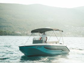 A speedboat navigates through serene waters, showcasing a scenic backdrop of lush hills — perfect for adventurous outings on the water.