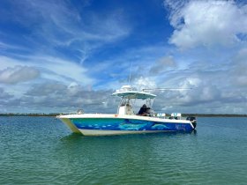 A vibrant speedboat, named 'Twin Vee,' is anchored in calm waters under a picturesque sky, showcasing its sleek design and inviting atmosphere for water adventures.