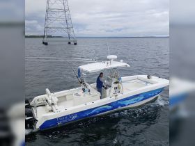 A man navigates a Twin Vee catamaran on the water, showcasing the thrill of fishing adventures and boating experiences.