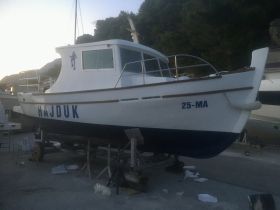 A detailed view of the 'HAJDUK' boat docked and ready for use, showcasing its hull and structure against a serene backdrop.