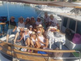 A lively group of friends enjoys a fun day on the boat, showcasing camaraderie and celebration in a beautiful marina setting.