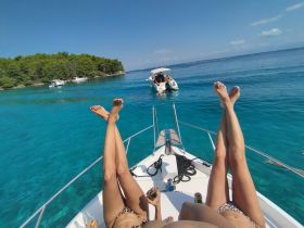 A group of friends relaxes on the bow of a boat, enjoying the stunning turquoise waters and sunshine — a perfect day for fun and relaxation on the water.