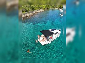 A group enjoys a refreshing swim in crystal-clear waters next to their boat, capturing the essence of a perfect summer day on the water.
