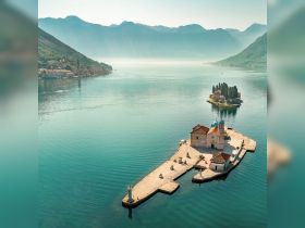 A stunning aerial view of picturesque islands in a tranquil bay, showcasing the serene beauty of the coastline and surrounding mountains — perfect for exploring by boat.
