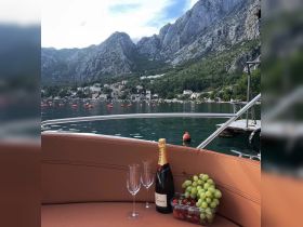 A beautifully arranged selection of champagne and fresh fruits on a boat, perfect for a relaxing day on the water surrounded by stunning mountain views.