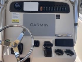 A detailed view of the helm and console area of a boat, showcasing the Garmin navigation system and steering wheel — essential for navigating the waters.