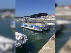A pontoon boat docked in a marina, showcasing its spacious design and ready for boat trips. Ideal for family outings and dolphin watching adventures.