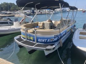 A pontoon boat docked at the marina, featuring comfortable seating and a rental advertisement — perfect for leisurely outings on the water.