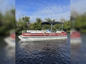 A pontoon boat navigates through serene waters, showcasing a relaxing day on the water with a guest enjoying the ride.