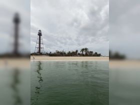 A scenic view featuring a lighthouse along the beach, with a child walking on the shore — a perfect representation of coastal beauty and family-friendly outings.