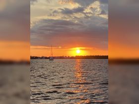 A serene sunset view featuring a yacht silhouetted against the vibrant sky, perfect for capturing the beauty of evening cruises.