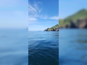 A serene view of a tranquil coastline under a clear blue sky, perfect for showcasing the beauty of nature during a boating adventure.