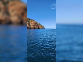 A stunning view of a rocky coastline against a clear blue sky, showcasing the natural beauty of the ocean — perfect for scenic boat tours.
