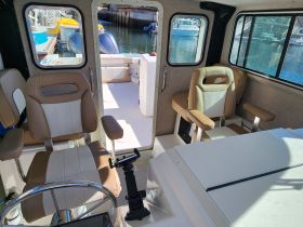 Interior view of a boat's helm and seating area, showcasing comfortable chairs and a clean, functional design ideal for navigation and relaxation.