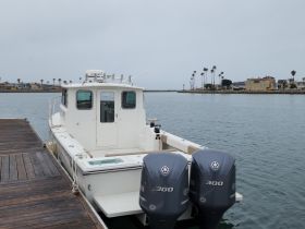 A rear view of a center console boat docked at the marina, showcasing its sleek design against a calm water backdrop.