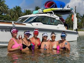 A lively group of friends enjoys a fun day in the water, celebrating with drinks beside their boat — perfect for summer parties and beach outings.