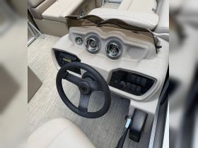 A detailed view of the helm and console area inside a boat, showcasing the steering wheel and control panel — perfect for navigating the waters.