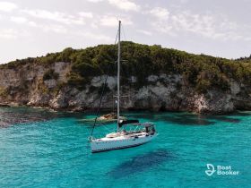 A stunning aerial view of a sailboat navigating through crystal-clear turquoise waters, surrounded by lush cliffs — perfect for showcasing sailing adventures in picturesque destinations.