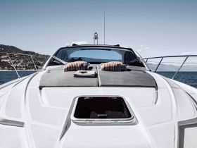 A stunning view of the front deck of a yacht, featuring comfortable seating and a serene backdrop of the coastline — perfect for luxury cruising.