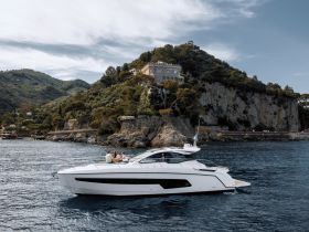 A stylish yacht glides through serene waters with a picturesque coastline in the background, perfect for group outings and scenic adventures.