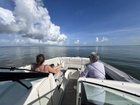 Two friends enjoy a relaxing day on the water, soaking in the beautiful scenery from the comfort of their boat.