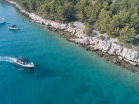Aerial view of boats navigating along a stunning coastline, showcasing the beauty of the turquoise waters and rocky shores — perfect for exploring hidden gems by sea.