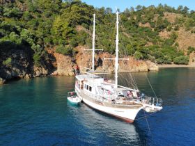 A stunning aerial view of a yacht anchored in a serene cove, surrounded by lush greenery — perfect for exploring coastal destinations.